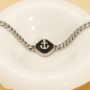 Détail de la chaîne gourmette en acier argenté avec un pendentif ancre octogonal en relief