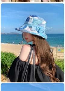 Detail of blue floral sun hat with mesh flower decoration on a sunny beach background