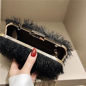 Detail view of black fringe evening clutch bag with gold chain strap and metal frame