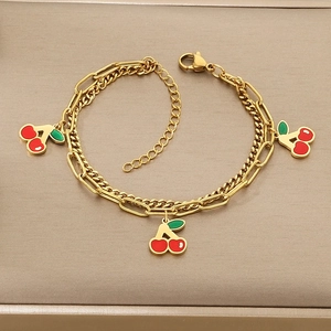 Detail of gold double-layer bracelet featuring red cherry enamel charms and lobster clasp