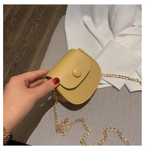 Gros plan d'un mini sac bandoulière jaune avec chaîne dorée tenu à la main