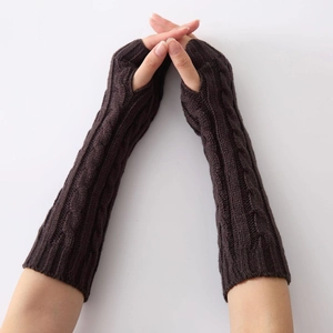 Close-up of dark brown cable knit arm warmers with fingerless design on a person arm