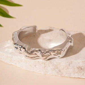 Detail of silver irregular wavy texture cuff bracelet on a natural white stone