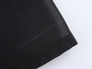 Gros plan sur la texture du tissu en mousseline noire et les coutures de la robe polo