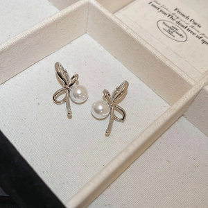 Detailed view of silver bow pearl earrings with crystal accents in a luxury gift box