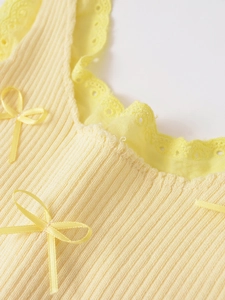 Détail du tricot côtelé avec bordure en dentelle délicate et nœud en soie jaune