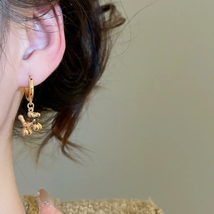 Close-up of a model wearing a gold plated balloon dog charm hoop earring with tiger eye stone
