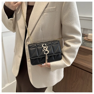 Detail of black quilted leather shoulder bag with gold S-logo, chain strap and tassel