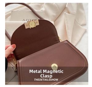 Detailed macro view of the magnetic metal closure on a brown leather shoulder bag