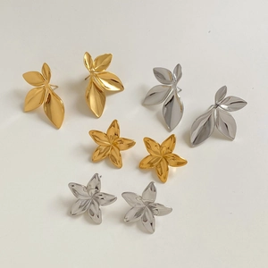 Detailed view of polished gold and silver clover leaf and flower studs on cream surface