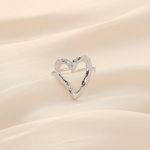Detail view of silver hollow heart ring with hammer texture on draped silk fabric