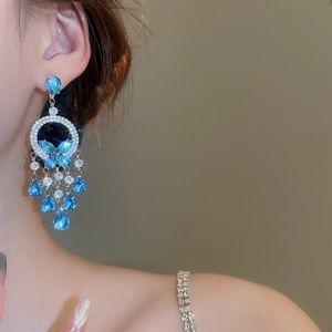 Detail of blue zircon butterfly tassel earrings worn by a model in elegant lighting