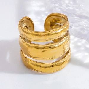 Gros plan d'une bague large dorée avec motifs ondulés et texture de métal martelé