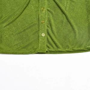 Detailaufnahme der grünen Strickjacke mit drei Knöpfen und feiner Stoffstruktur