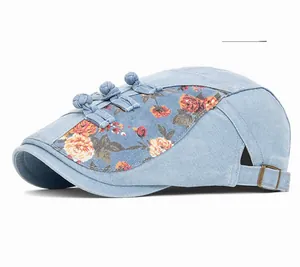 Détail du béret en jean bleu clair avec panneaux floraux et boutons vintage à brandebourgs