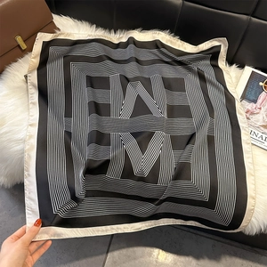 Close-up of geometric striped silk scarf on plush mat with magazine and handbag