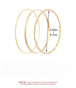 Detailed view of three gold alloy bangles with beaded, hammered, and glitter textures