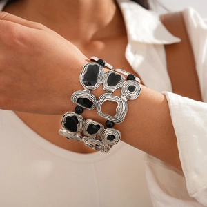 Close-up of wide cuff bracelet featuring silver geometric frames and black resin inlays