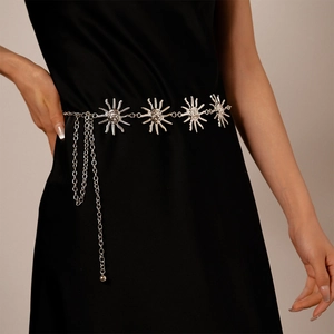 Detail of silver vintage sun portrait chain belt on a black dress highlighting metal texture