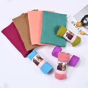 Flat lay di sciarpe in cotone e lino in vari colori con fiori secchi e rivista