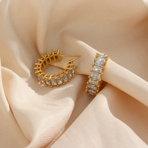 Détail de boucles d'oreilles C plaquées or 18K avec zircons rectangulaires sur satin