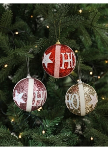 Close-up of glittery red, pink, and gold Christmas ornaments with star and HO pattern