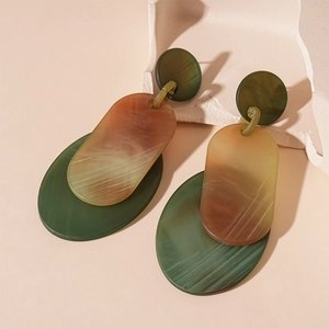 Gros plan de boucles d'oreilles géométriques en acrylique à texture marbrée vert et ambre