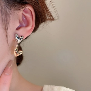 Detailed close-up of a model wearing stylish heart-shaped two-tone metal earrings