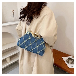 Detail of vintage denim shell bag featuring blue quilted pattern and pearl clasp closure