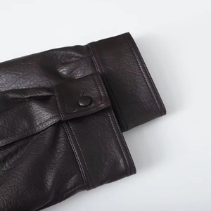 Detail of dark brown faux leather jacket cuff with adjustable button strap and double stitching