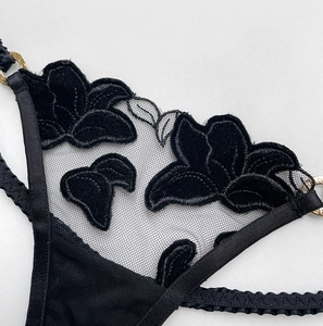 Detail of black velvet floral embroidery on mesh thong with metal ring buckle