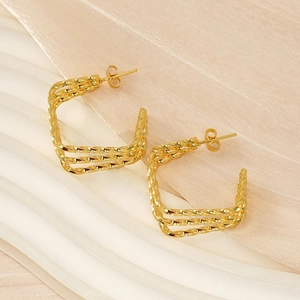 Detailed view of golden twisted rope C-shaped stud earrings on soft textured fabric