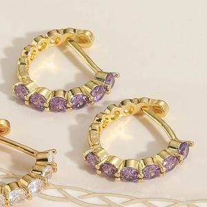 Vue détaillée macro de boucles d'oreilles en C dorées avec zircons violets et blancs