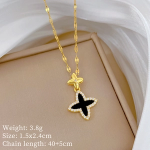 Close-up of gold clover necklace with diamonds on beige gift box showing product specs