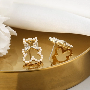 Macro view of gold teddy bear earring with white pearls and sparkling crystal bowknot