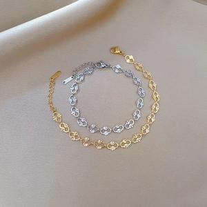 Detail of gold and silver hollowed chain bracelets with S-STEEL tag on beige fabric