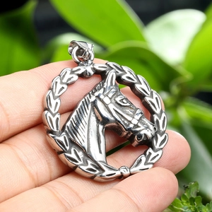 Detailed close-up of a vintage silver horse head pendant with laurel wreath engraving