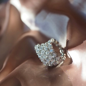 Macro shot of silver luxury wedding ring with multi-layer pave diamonds on champagne silk