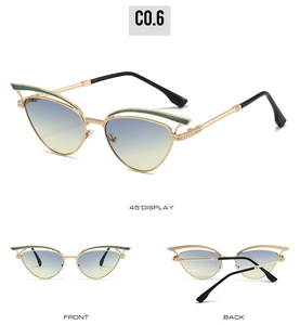 Detail view of hollow cat-eye sunglasses with gold metal frame and green enamel accents