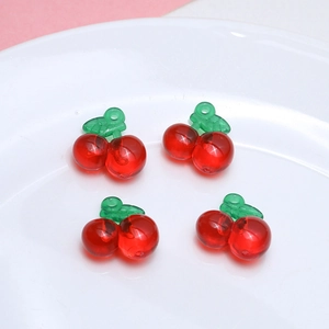Macro shot of red cherry resin pendants for DIY jewelry making on white ceramic plate