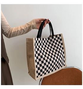 Detailed close-up of a vintage linen tote bag featuring a classic black and white checkerboard pattern