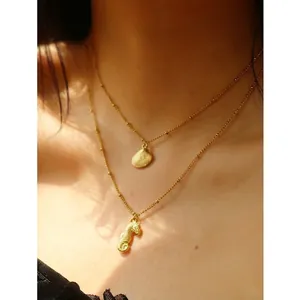 Gold double-layered necklace featuring seahorse and shell pendants on a female model