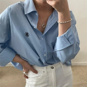 Close-up of light blue long-sleeved button-up shirt featuring a circular black graphic logo