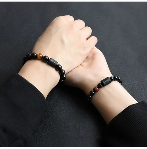 Close-up of couple wearing 8mm black beaded bracelets with tiger eye and zodiac symbols