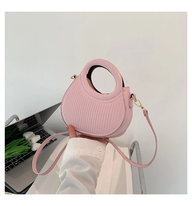 Detailed side view of pink saddle bag with vertical striped embossing and round handle