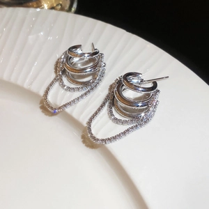 Détail macro de boucles d'oreilles à pampilles en argent avec zircons sur plateau céramique