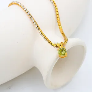 Macro view of 18K gold plated tennis chain with round light green gemstone pendant