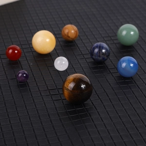 Solar system crystal stones set with nine polished gemstones on a black grid background