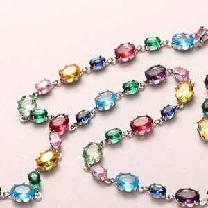 Detail shot of multi-color oval gemstones set in silver claw chain for luxury necklace