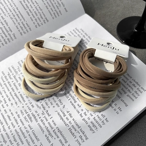 Earth-toned elastic hair ties set on open book, minimalist high-stretch fabric scrunchies